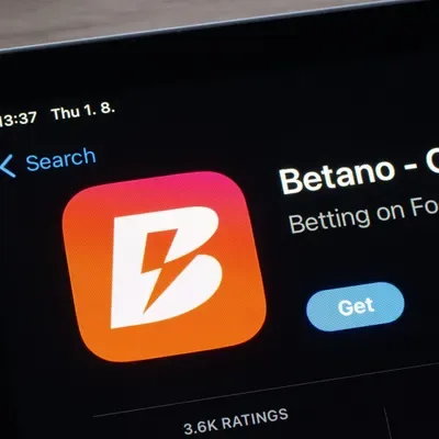 Fotografía de un teléfono que muestra la ficha de la app de betano en una tienda de aplicaciones, con el botón «Get», la categoría de apuestas y una valoración de 3.6K reseñas.